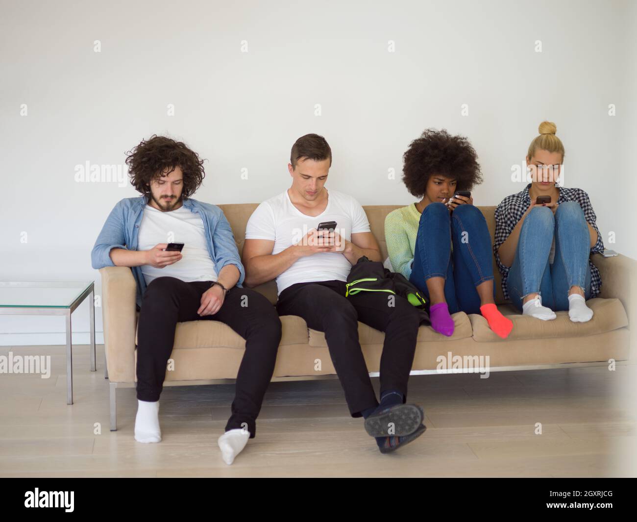 Groupe multiethnique de jeunes gens assis sur un canapé à la maison à regarder,smartphone, smartphone, antisocial en toxicomanie Banque D'Images
