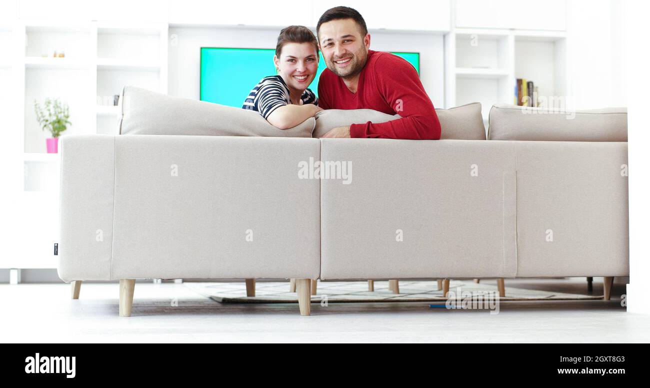 Jeune couple sur le canapé à regarder la télévision ensemble dans leur maison de luxe Banque D'Images