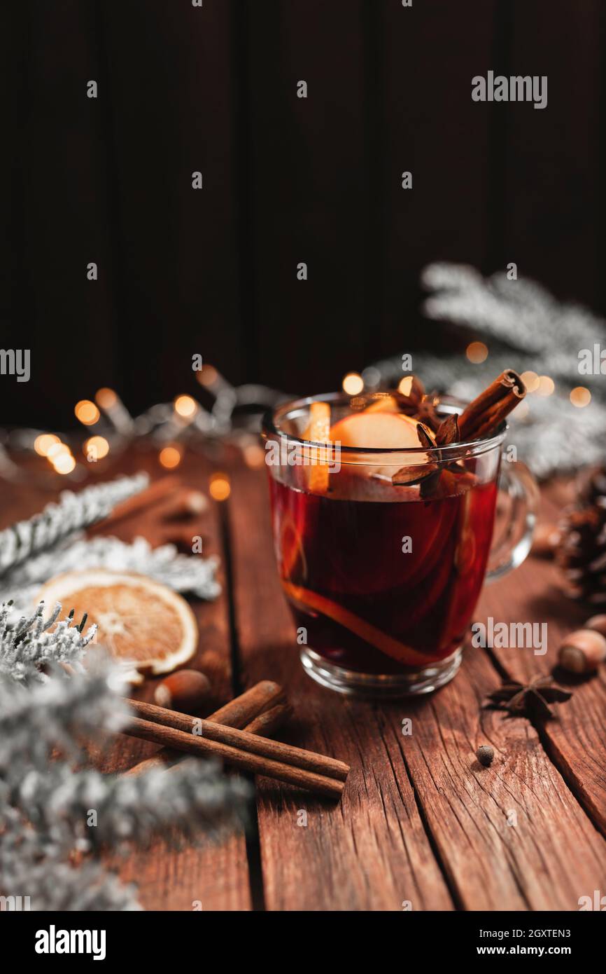 Photo concept de l'heure de Noël.Tasse ou mug en verre avec vin chaud à l'intérieur sur table et arrière-plan en bois.Décorations de Noël, lumières, composition avec Banque D'Images