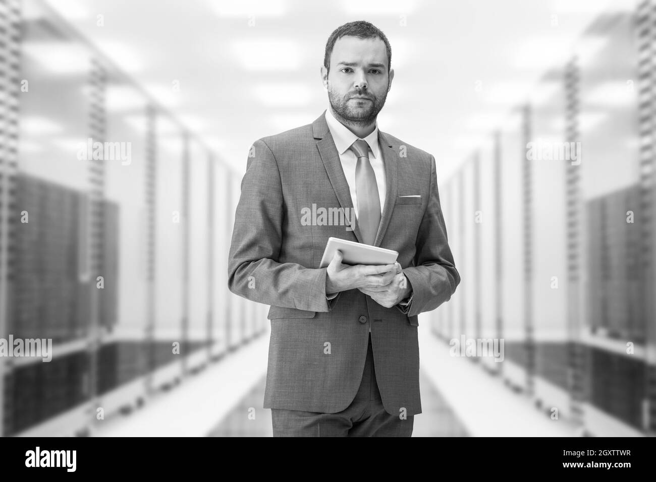 Portrait of young businessman in server room using tablet Banque D'Images
