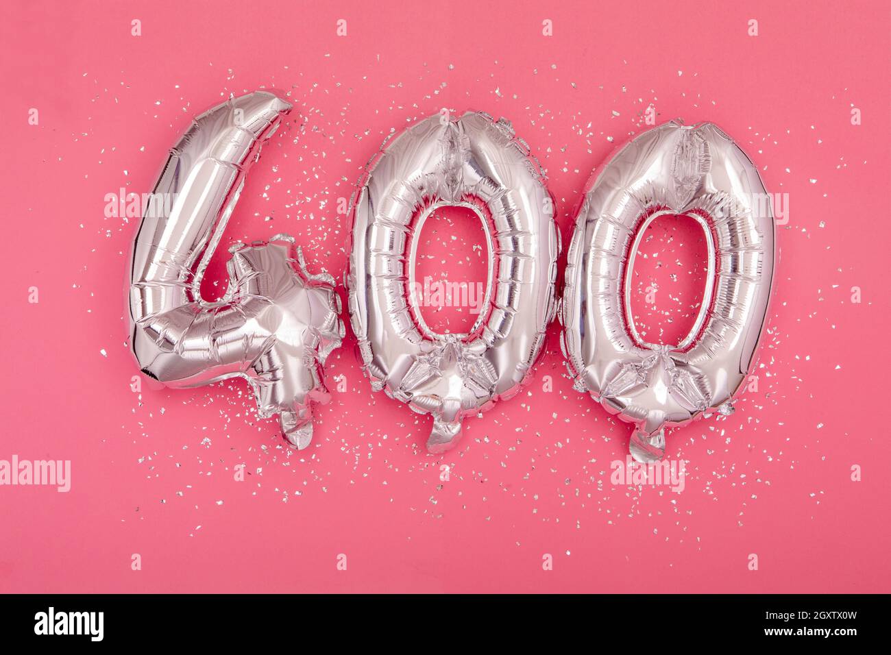 De dessus de ballons brillants argentés démontrant le numéro 400 quatre cent fond rose avec paillettes éparpillées Banque D'Images