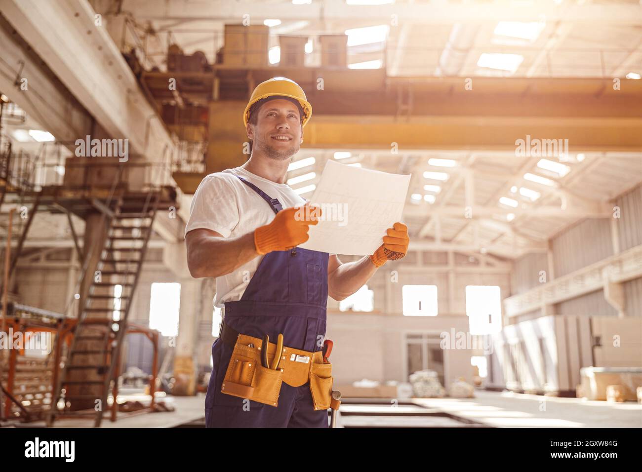 Homme joyeux travaillant dans le cadre d'un plan architectural de bâtiment Banque D'Images