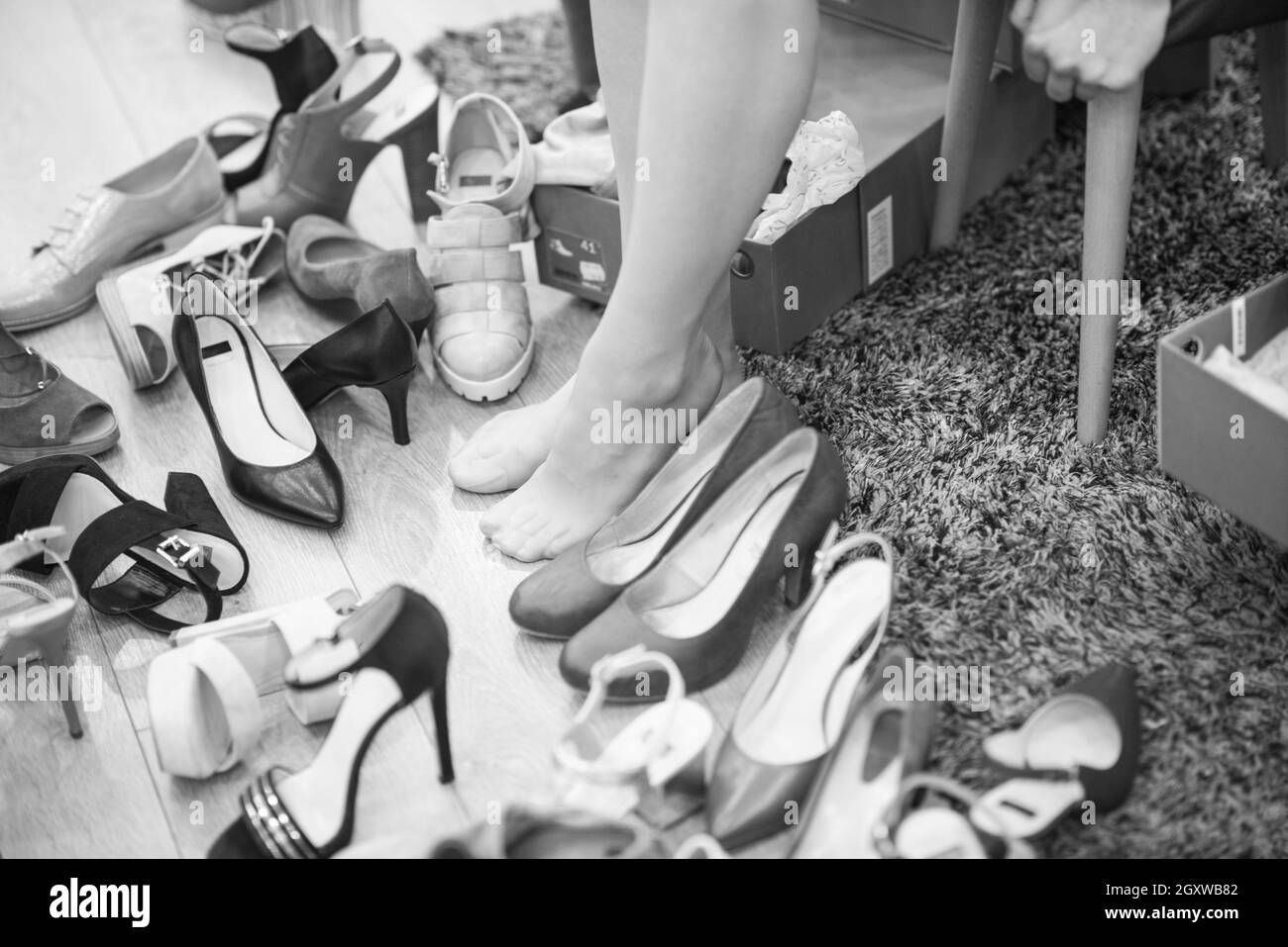 Choix difficile. Close-up of young woman sitting in shoe store alors que différents pose près de ses chaussures Banque D'Images