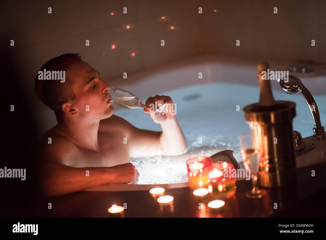 Jeune homme séduisant bénéficie d'de vous détendre dans le jacuzzi avec  bougies et champagne à luxury resort spa Photo Stock - Alamy