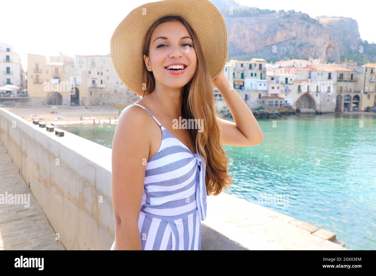 Fille riant dans un chapeau de paille regardant dans l'appareil photo à Cefalu, Sicile Banque D'Images