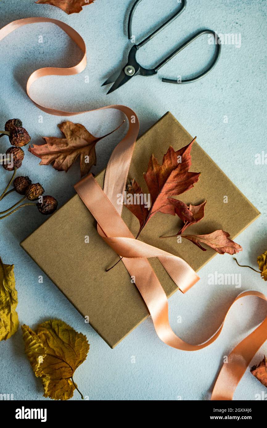 Boîte cadeau automnale attachée avec un ruban et des décorations de feuilles d'automne séchées sur une table Banque D'Images