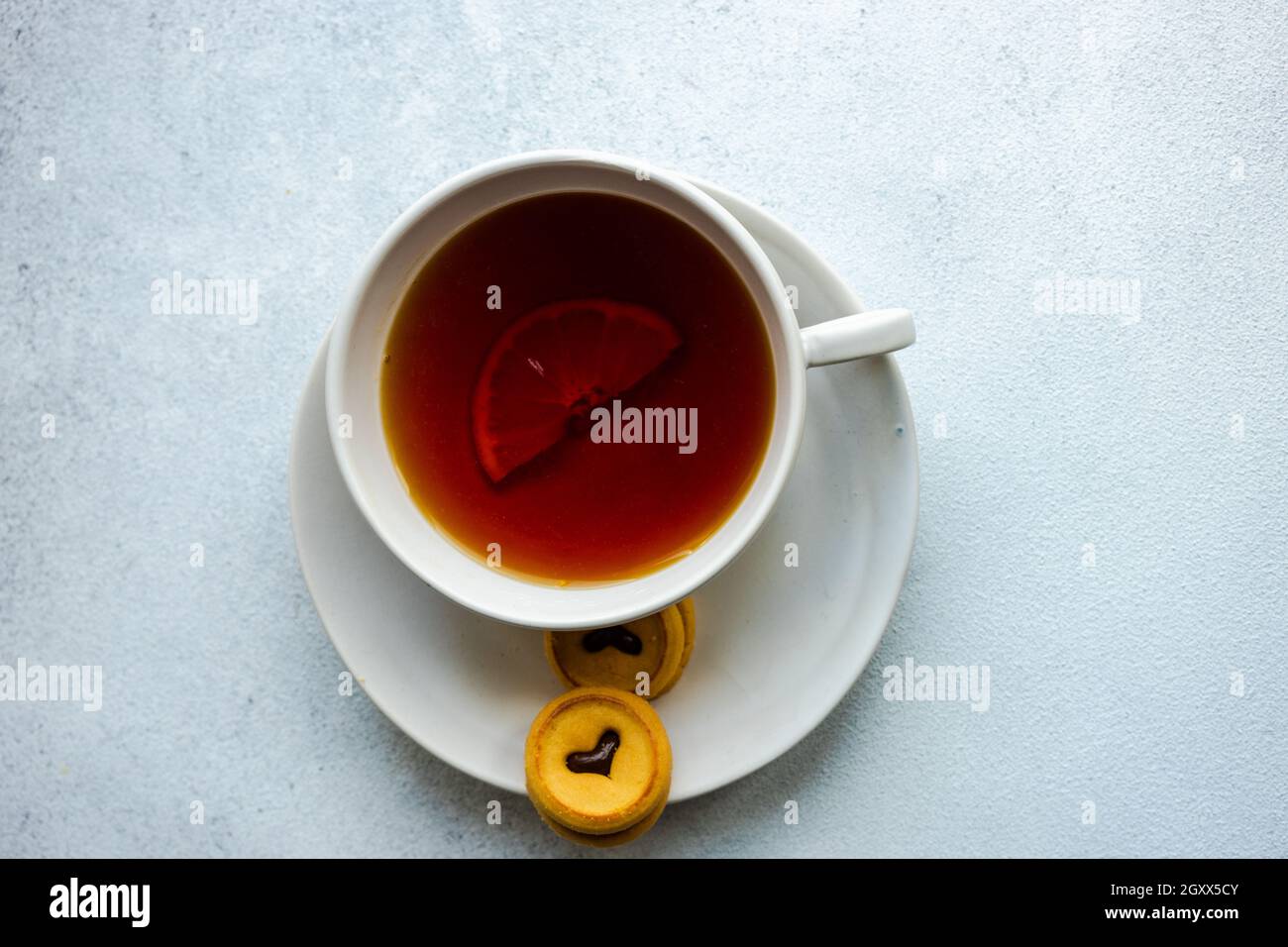 Tasse de thé avec une tranche de citron et deux biscuits Banque D'Images