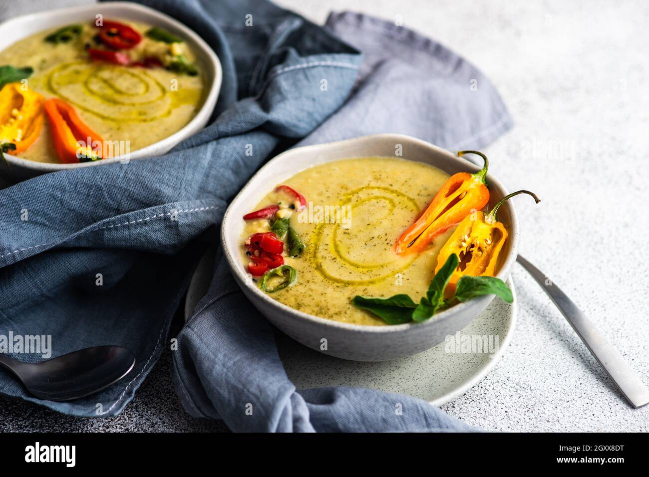 Deux bols de soupe crémeuse aux pois chiches épicés avec piments, origan et garniture de graines de sésame noir Banque D'Images