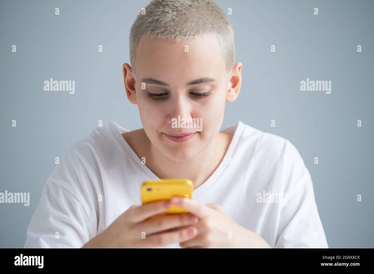Une jeune femme pensive avec une courte coupe de cheveux parle de manière réfléchie sur un téléphone portable sur fond blanc Banque D'Images