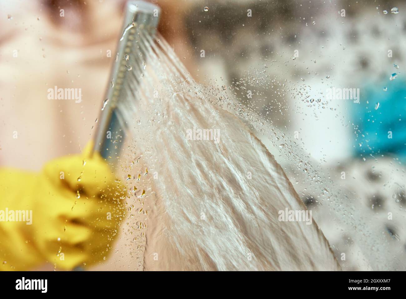 Femme en caoutchouc jaune gants nettoie verre salle de bains douche cabine. Nettoyage de la maison Banque D'Images