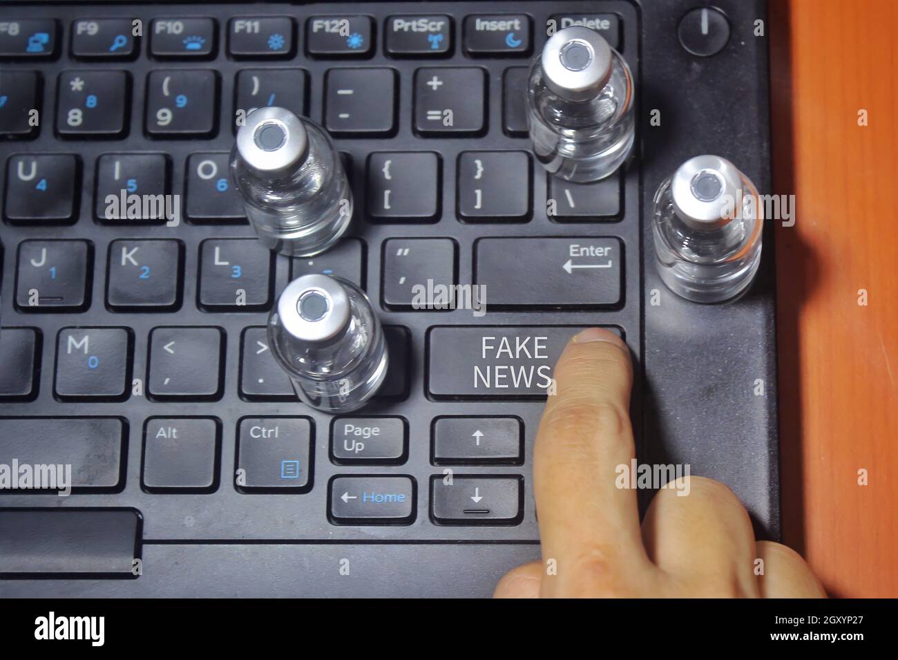 Touche de pression du doigt étiquetée avec du texte FAUSSES NOUVELLES et entourée d'un flacon en verre Banque D'Images