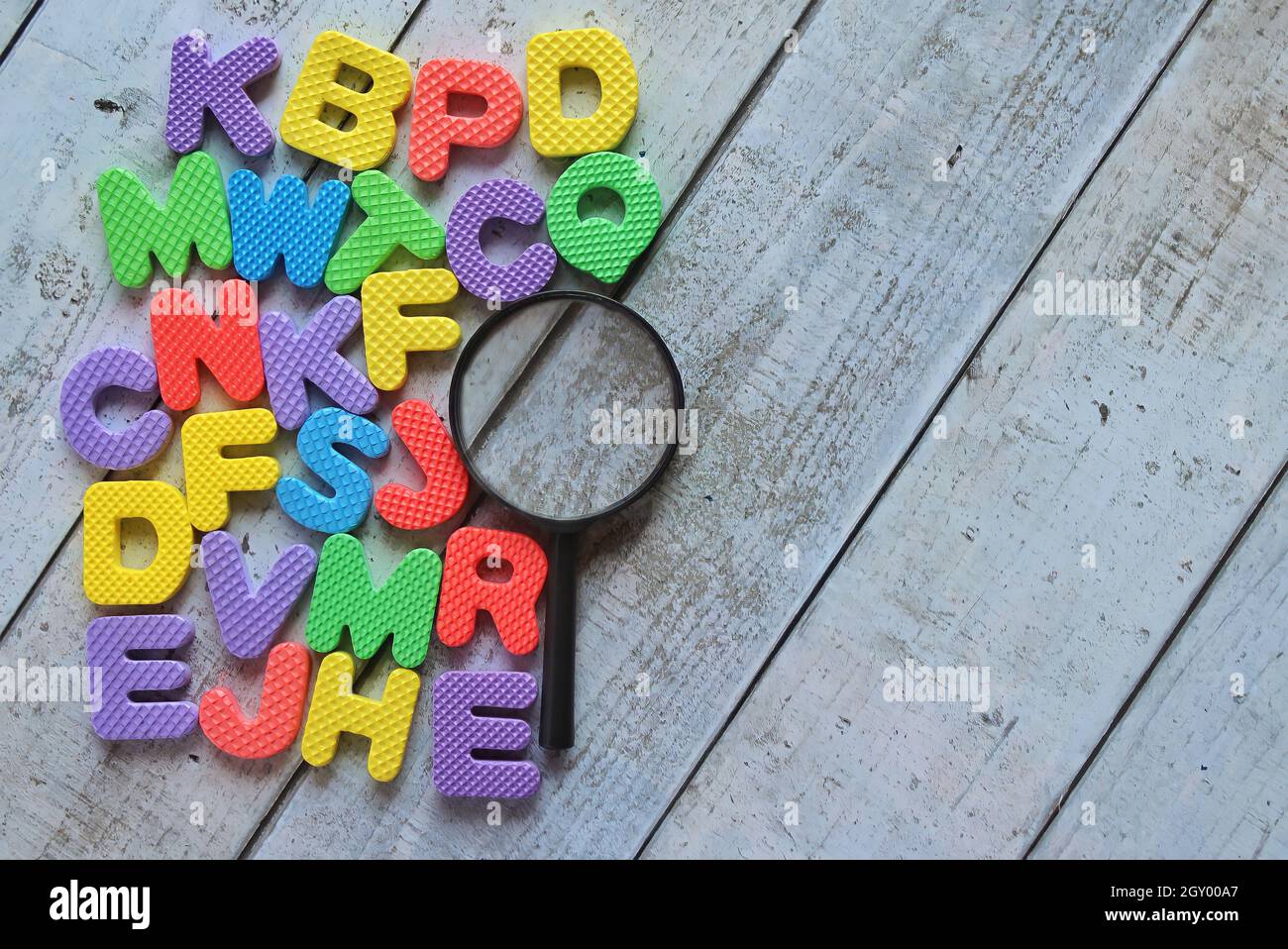 Vue de dessus de la loupe et de l'alphabet coloré sur une table en bois. Copier l'espace pour le texte. Banque D'Images