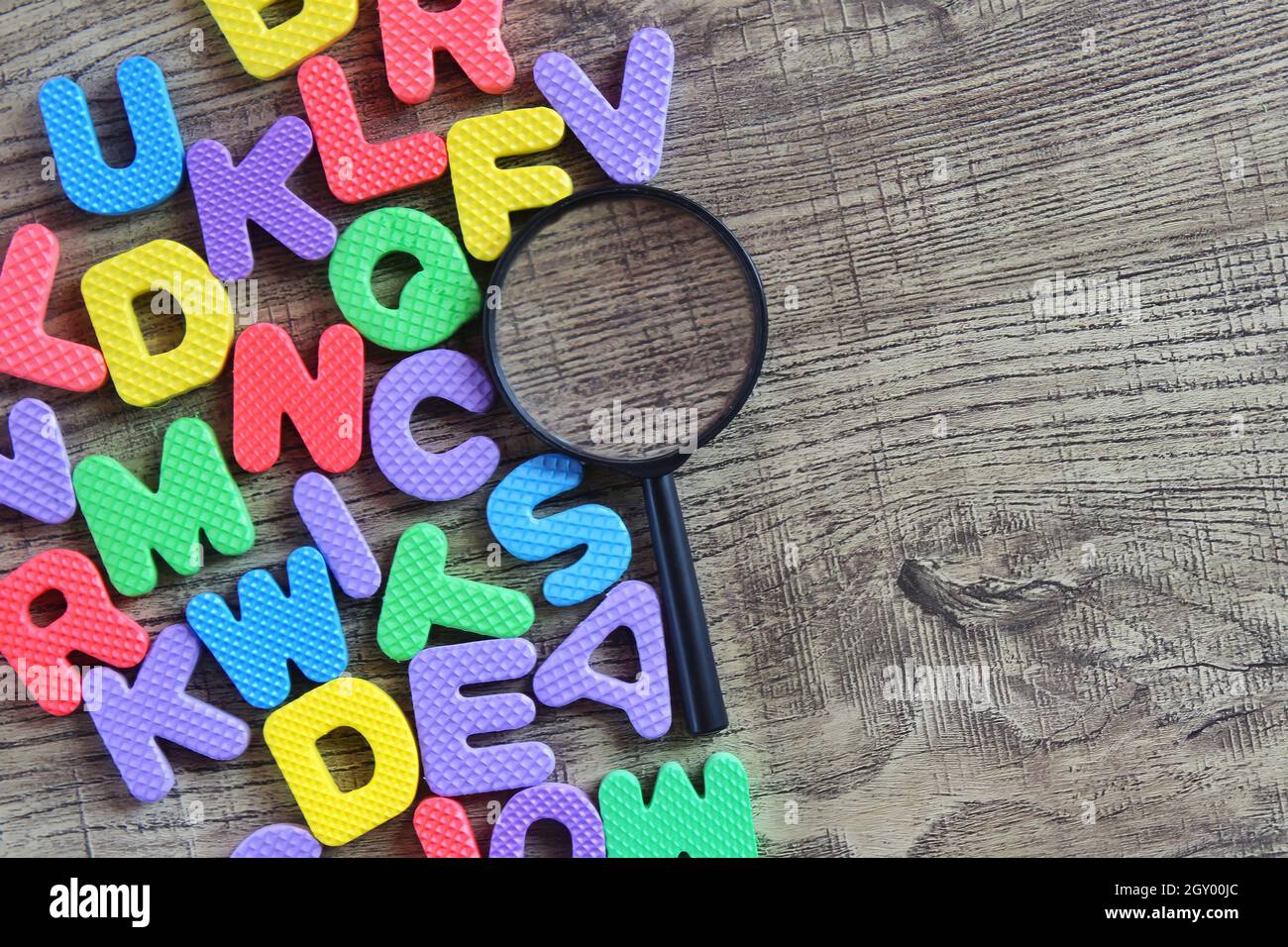 Vue de dessus de la loupe et de l'alphabet coloré sur une table en bois. Copier l'espace pour le texte. Banque D'Images