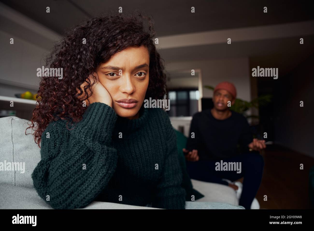 Femme de race mixte en colère contre le copain noir tout en luttant sur le canapé dans l'appartement moderne Banque D'Images