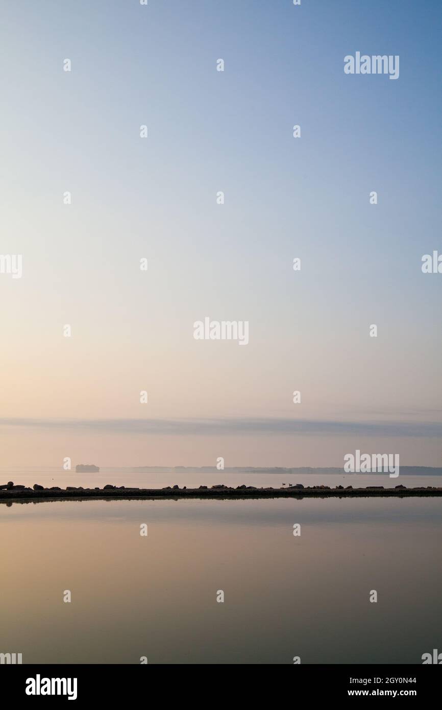 Paisible scène de lac où un affleurement rocheux se reflète dans les eaux calmes Banque D'Images