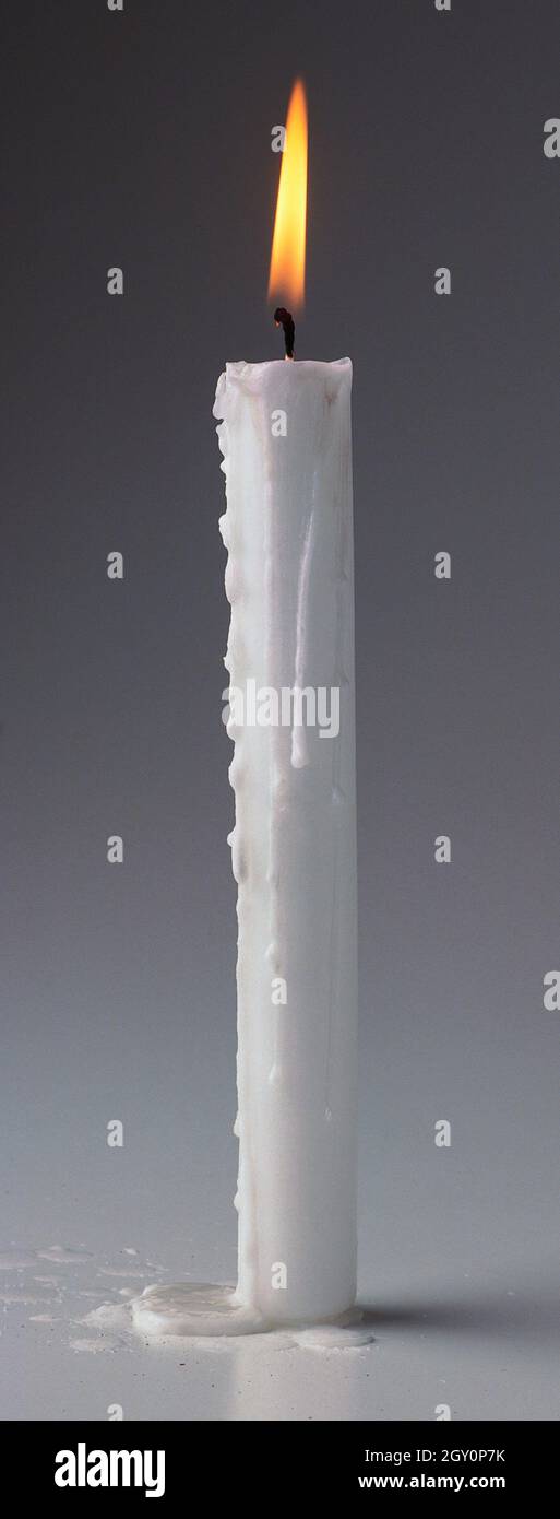 Une bougie blanche qui brûle, de la cire qui coule sur le côté Photo Stock  - Alamy