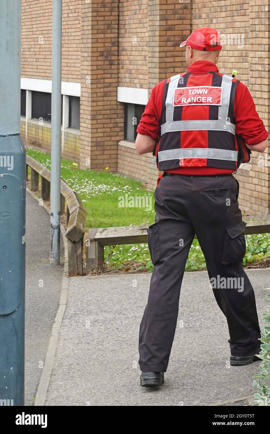 Rugby Town Ranger dans un centre-ville en uniforme rouge destiné aux activités criminelles, avec des liaisons radio directes avec des opérateurs de vidéosurveillance et la police Warwickshire UK Banque D'Images