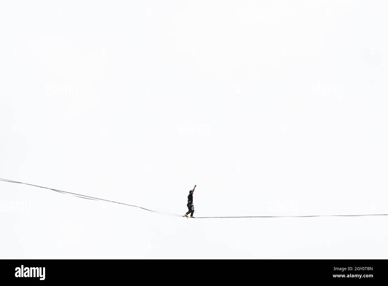 Un marcheur sur corde raide marche sur la corde à haute altitude. Banque D'Images