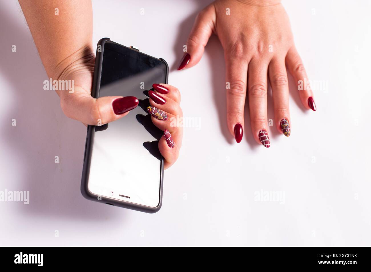 Jeunes femmes mains avec manucure rouge gros plan, sur fond blanc. Banque D'Images