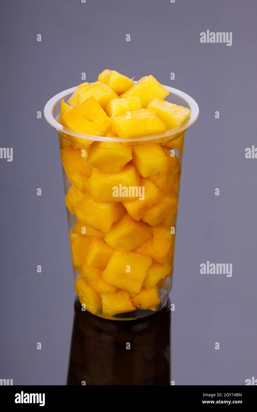 Cubes de mangue mûrs ou morceau découpé disposé dans un verre transparent avec fond noir. Banque D'Images