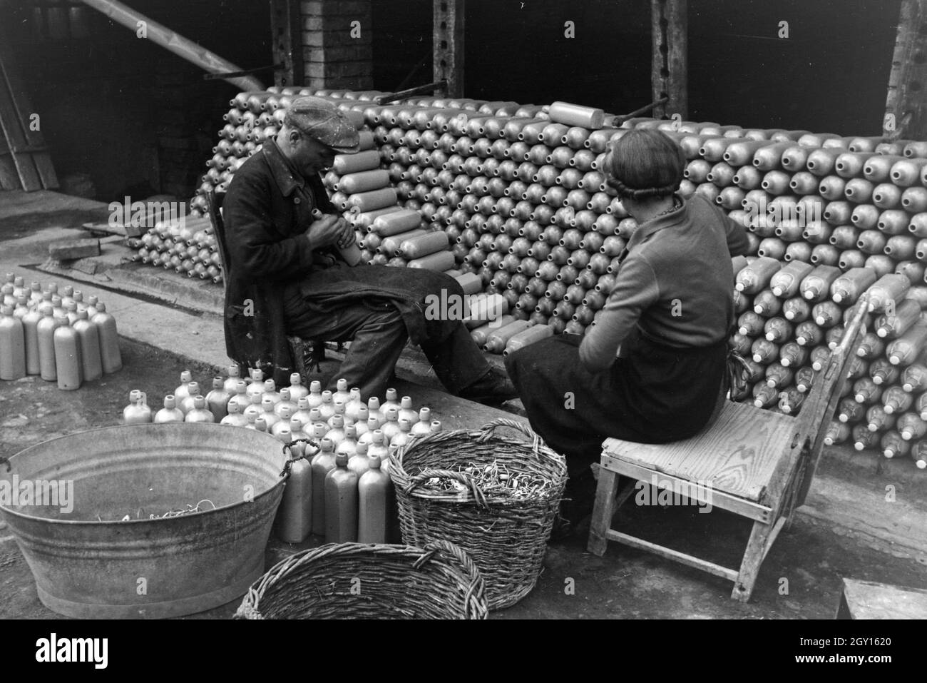 Zwei aus dem Töpfermeister Kannenbäckerland bringen unter freiem Himmel un Steingutflaschen Bügelverschlüsse die der, Deutschland 1930 er Jahre. Deux maîtres-potiers à partir de la fixation de la balançoire Kannenbäckerland sont tops à l'extérieur des bouteilles en grès, Allemagne 1930. Banque D'Images