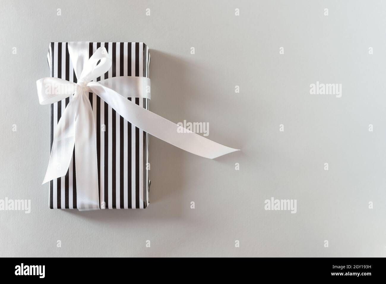 Emballage cadeau à rayures noires et blanches.Vue de dessus d'un cadeau  monochrome strict avec un ruban blanc satiné.Design minimaliste conceptuel  d'un anniversaire c Photo Stock - Alamy