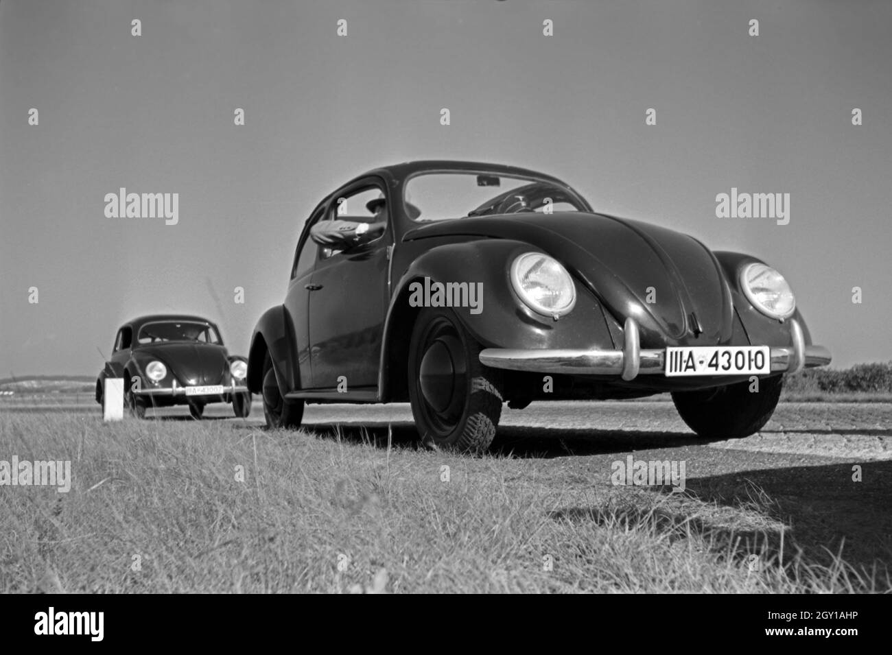 Zwei Modelle des Volkswagen Käfer, oder KdF Wagen, mit offenem und geschlossenem Dach am Rande eines Teststrecke bei Berlin, Deutschland 1930er Jahre. Deux modèles de la coccinelle de Volkswagen KdF, ou voiture, avec toit fermé et ouvert près de la piste d'essai près de Wolfsburg, Allemagne 1930. Banque D'Images