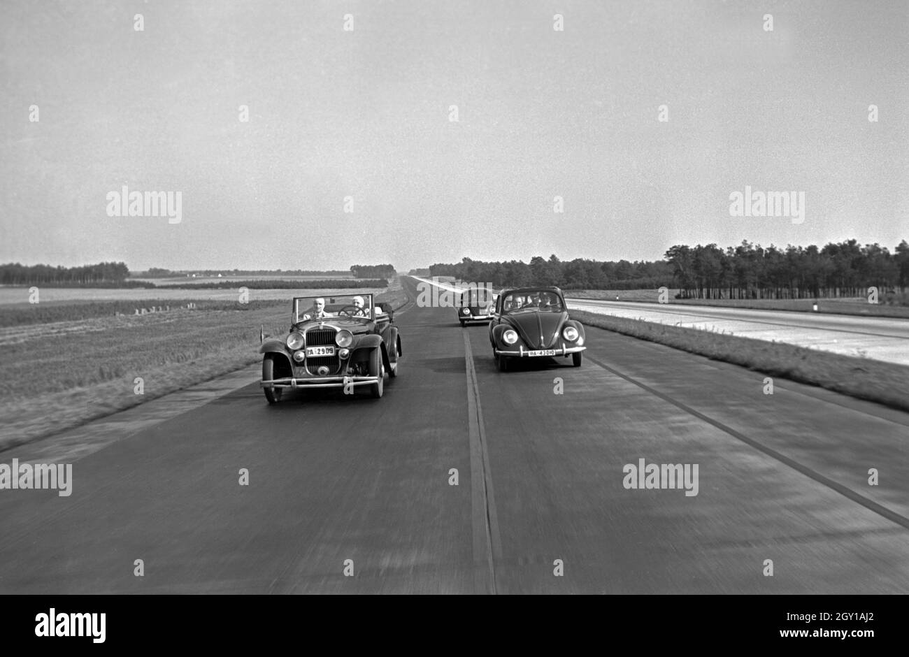 Zwei Modelle des Volkswagen Käfer, oder KdF Wagen, mit offenem und geschlossenem Dach werden auf der Reichsautobahn bei einem Wolfsburg Cabrio überholt, Deutschland 1930 er Jahre. Deux modèles de la coccinelle de Volkswagen KdF, ou voiture, avec toit ouvert et fermé sont dépassés par une décapotable sur la Reichsautobahn autoroute près de Wolfsburg, Allemagne 1930. Banque D'Images