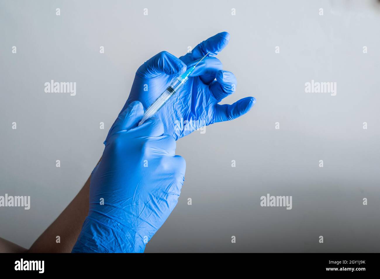les mains du médecin avec des gants en caoutchouc bleu, tenant et tapotant une seringue prête pour la vaccination. outils de vaccination et de protection (covid-19, grippe Banque D'Images