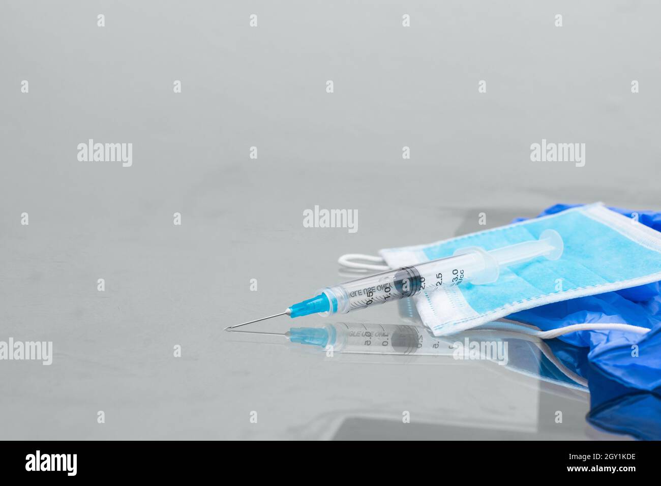 seringue sur le dessus du masque de protection bleu et gants en caoutchouc bleu, sur la table en verre, prêts à être utilisés pour la vaccination. instruments de vaccination (c Banque D'Images