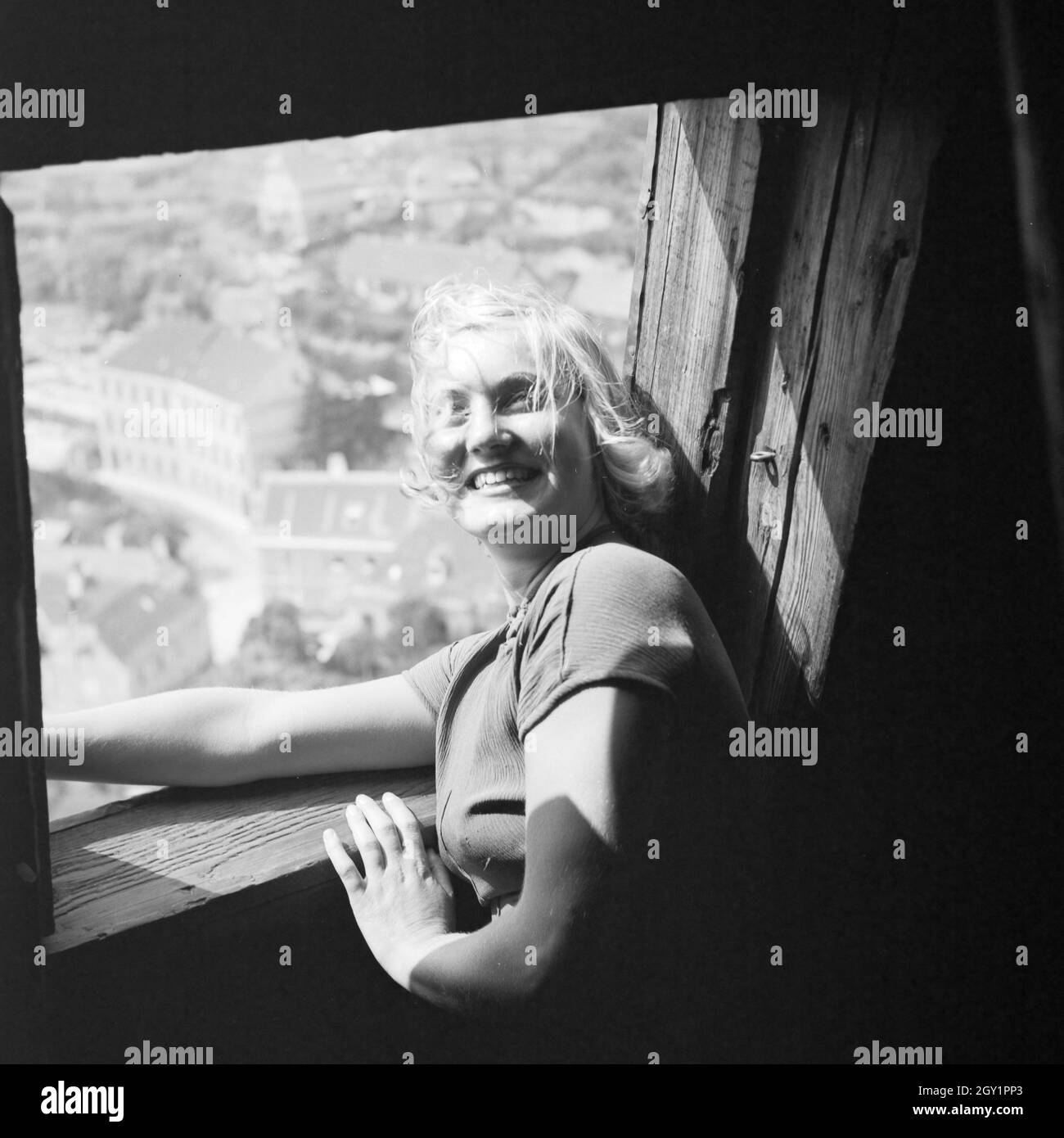 Eine junge Frau am Dachfenster eines Kirchturms, 1930er Jahre Deutschland. Une jeune femme sur la fenêtre d'un beffroi garret, Allemagne 1930. Banque D'Images