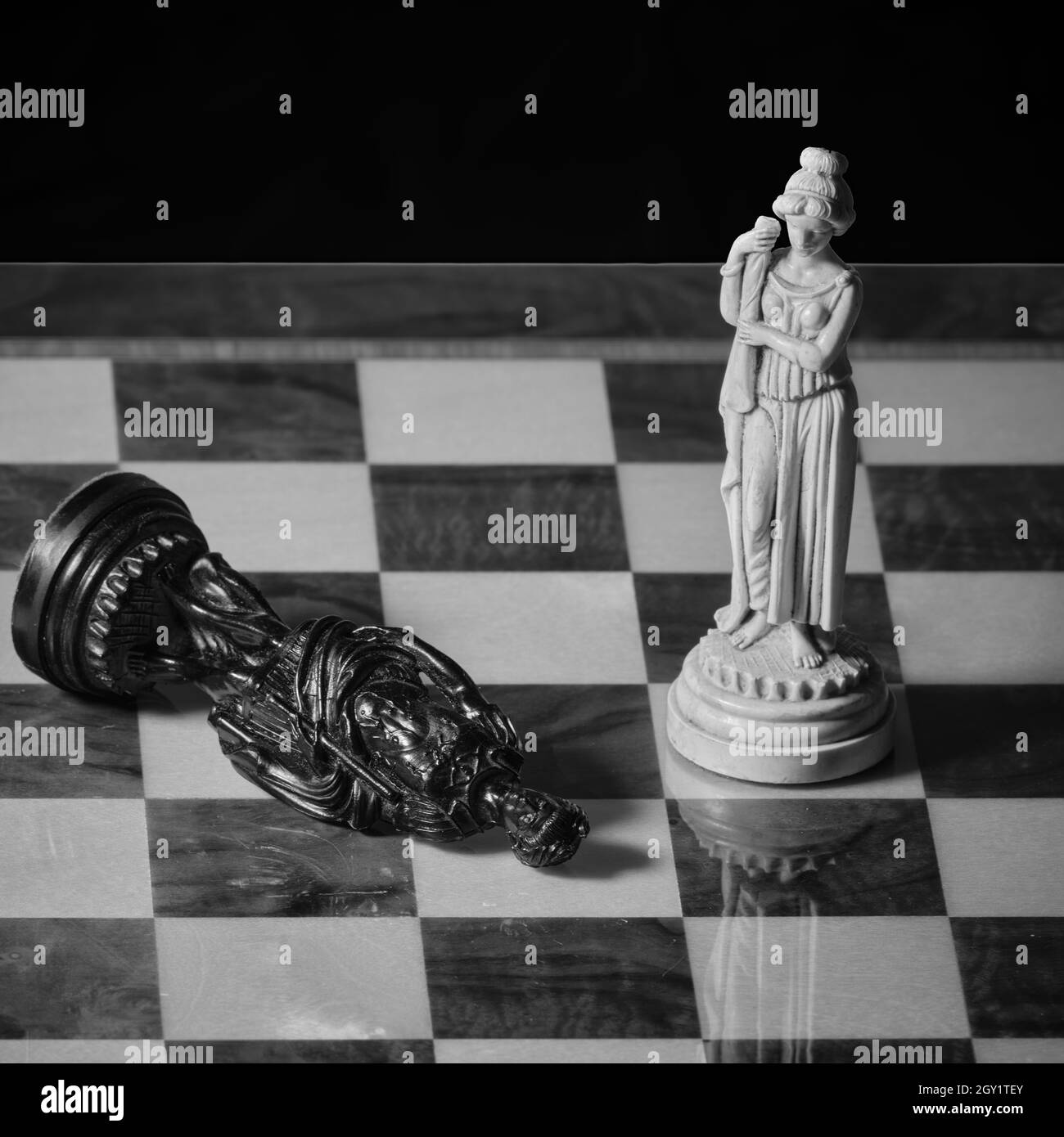 De vieilles pièces d'échecs sur un échiquier, une reine blanche et un roi noir déchu en noir et blanc Banque D'Images
