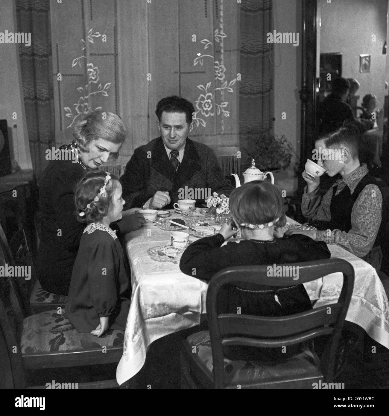 Eine Familie sitzt im Wohnzimmer am Kaffeetisch, Deutschland 1930er Jahre. Une famille assise au tabele, ayant un café, Allemagne des années 1930. Banque D'Images
