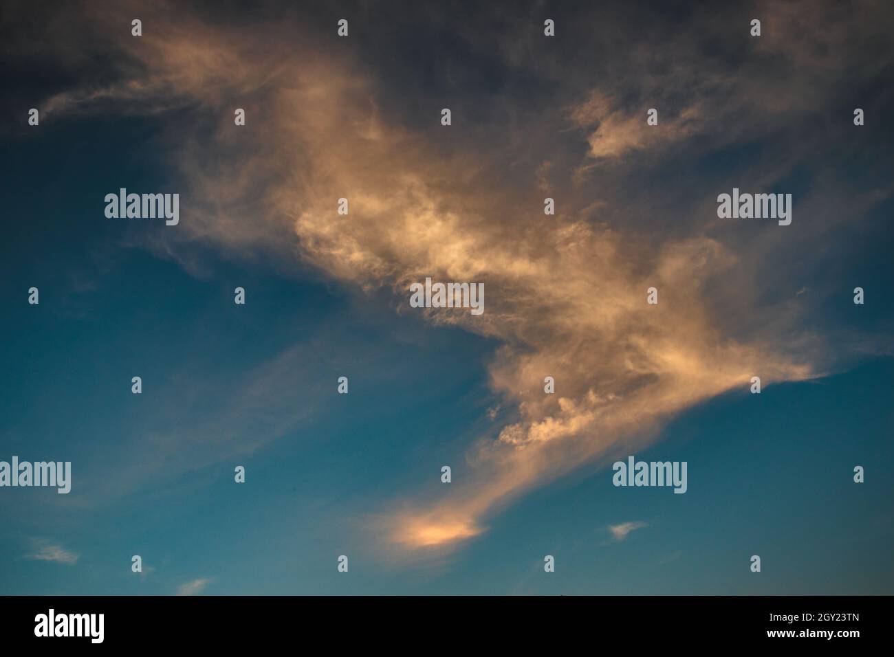 ciel turquoise, couvert de touffes de nuages blancs parsemés de taches ensoleillées et ombragés en orange. Banque D'Images