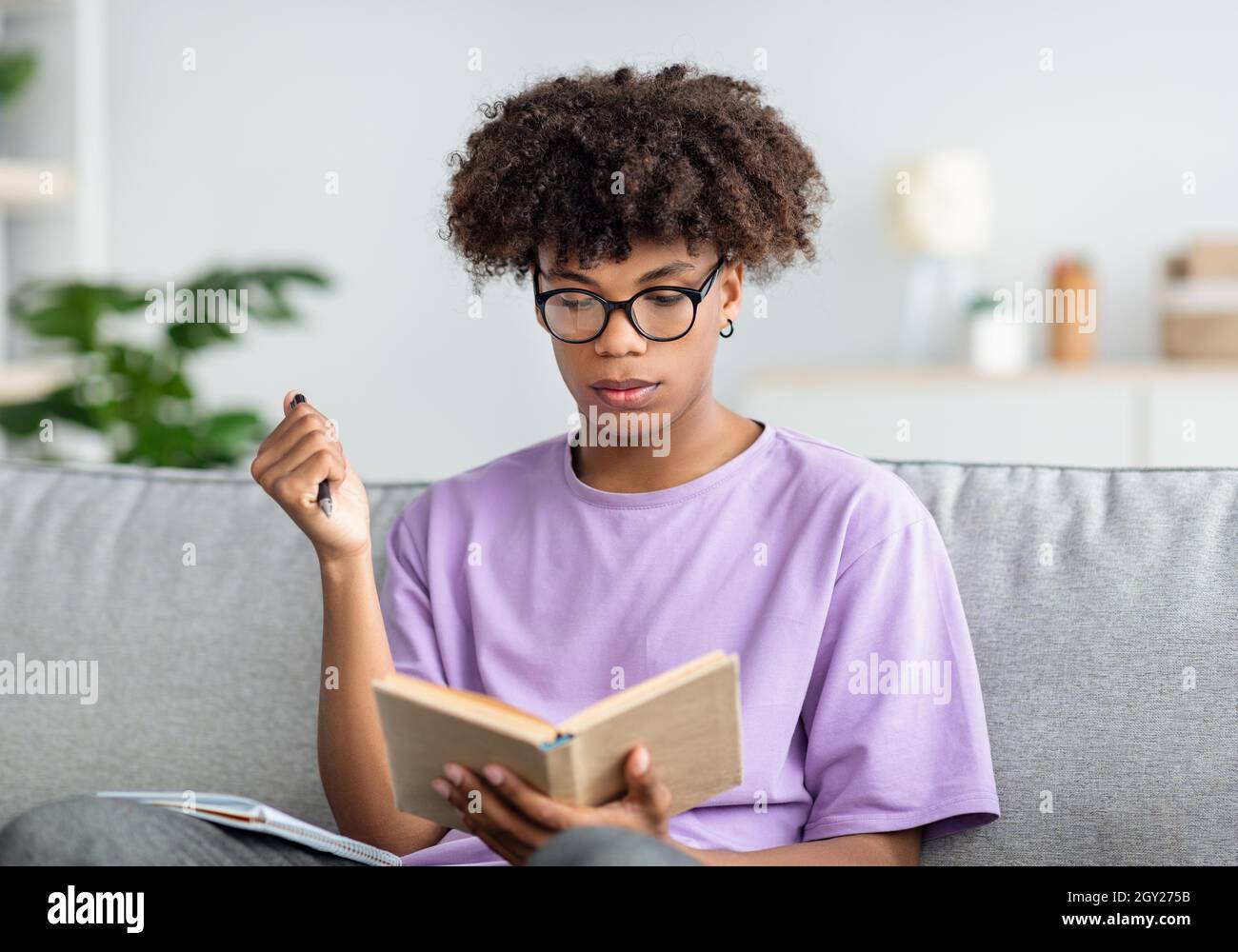 Jeunes noirs sérieux avec des manuels prenant des notes, étudiant à la maison, se préparer à l'examen Banque D'Images