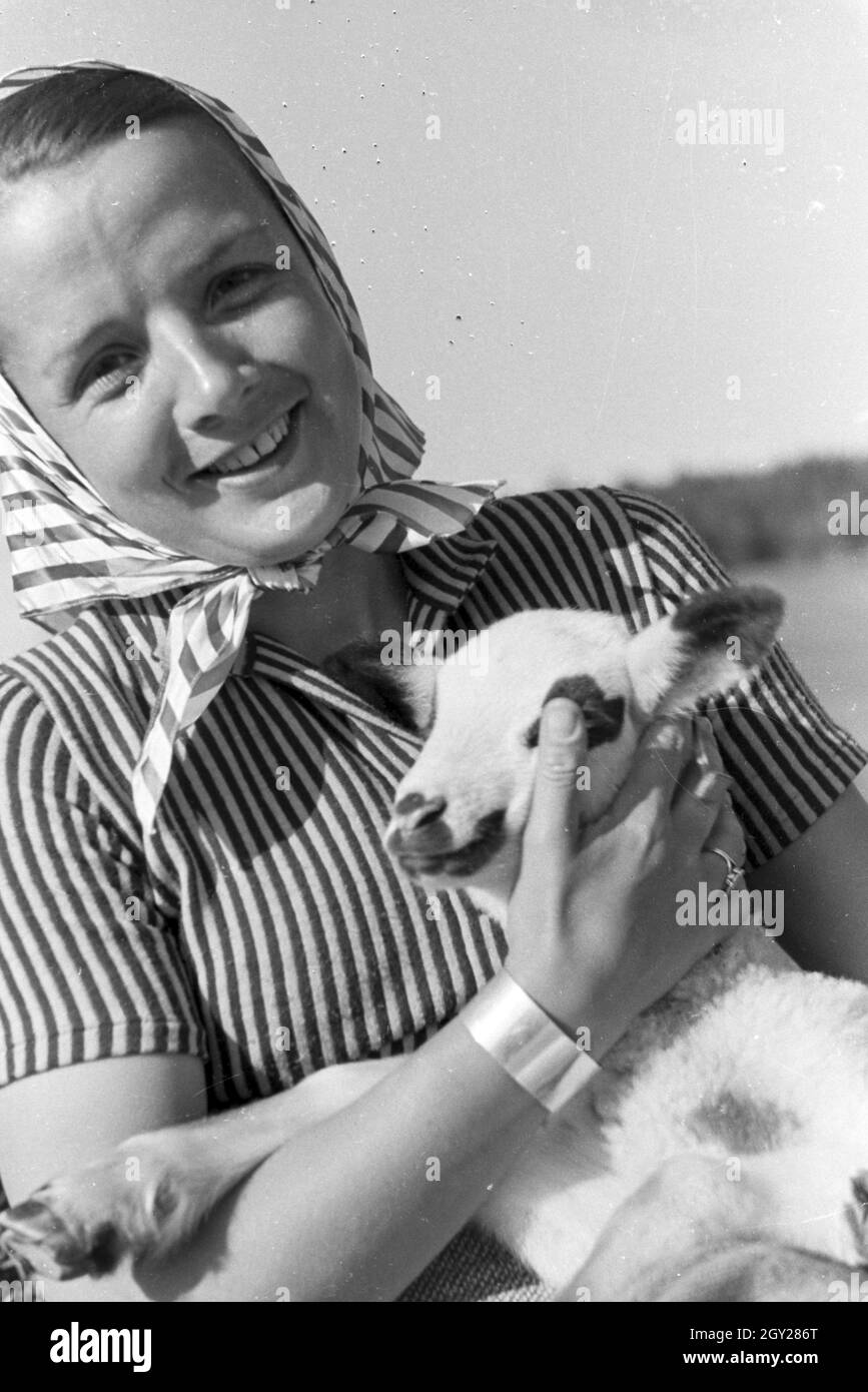 Eine junge Frau mit einem gescheckten Zicklein, St Märgen im Südschwarzwald, Deutschland 1930 er Jahre. Une jeune femme tenant une chèvre tachetée kid, St Märgen dans le sud de la Forêt-Noire, Allemagne 1930. Banque D'Images