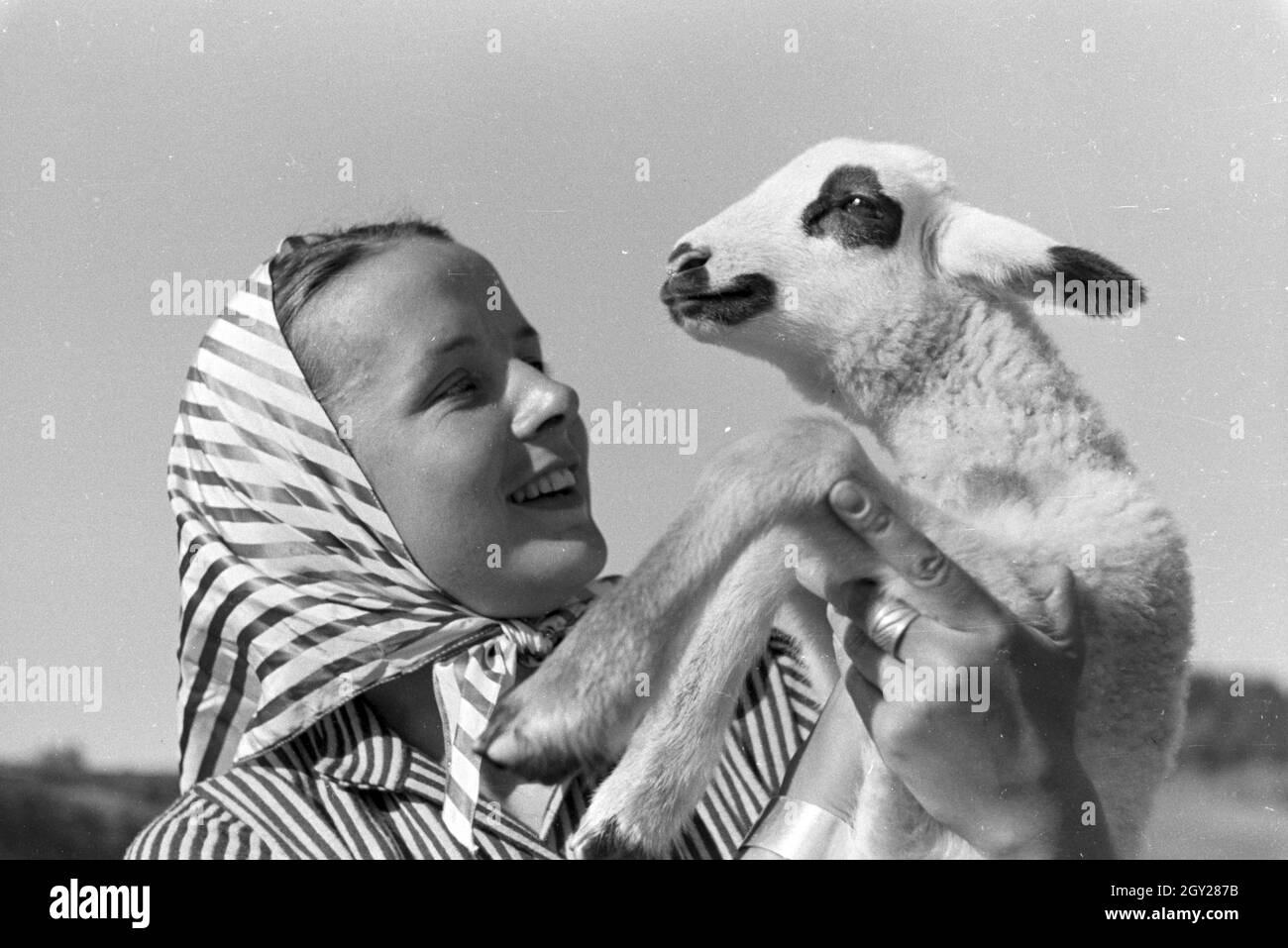 Eine junge Frau mit einem gescheckten Zicklein, St Märgen im Südschwarzwald, Deutschland 1930 er Jahre. Une jeune femme tenant une chèvre tachetée kid, St Märgen dans le sud de la Forêt-Noire, Allemagne 1930. Banque D'Images