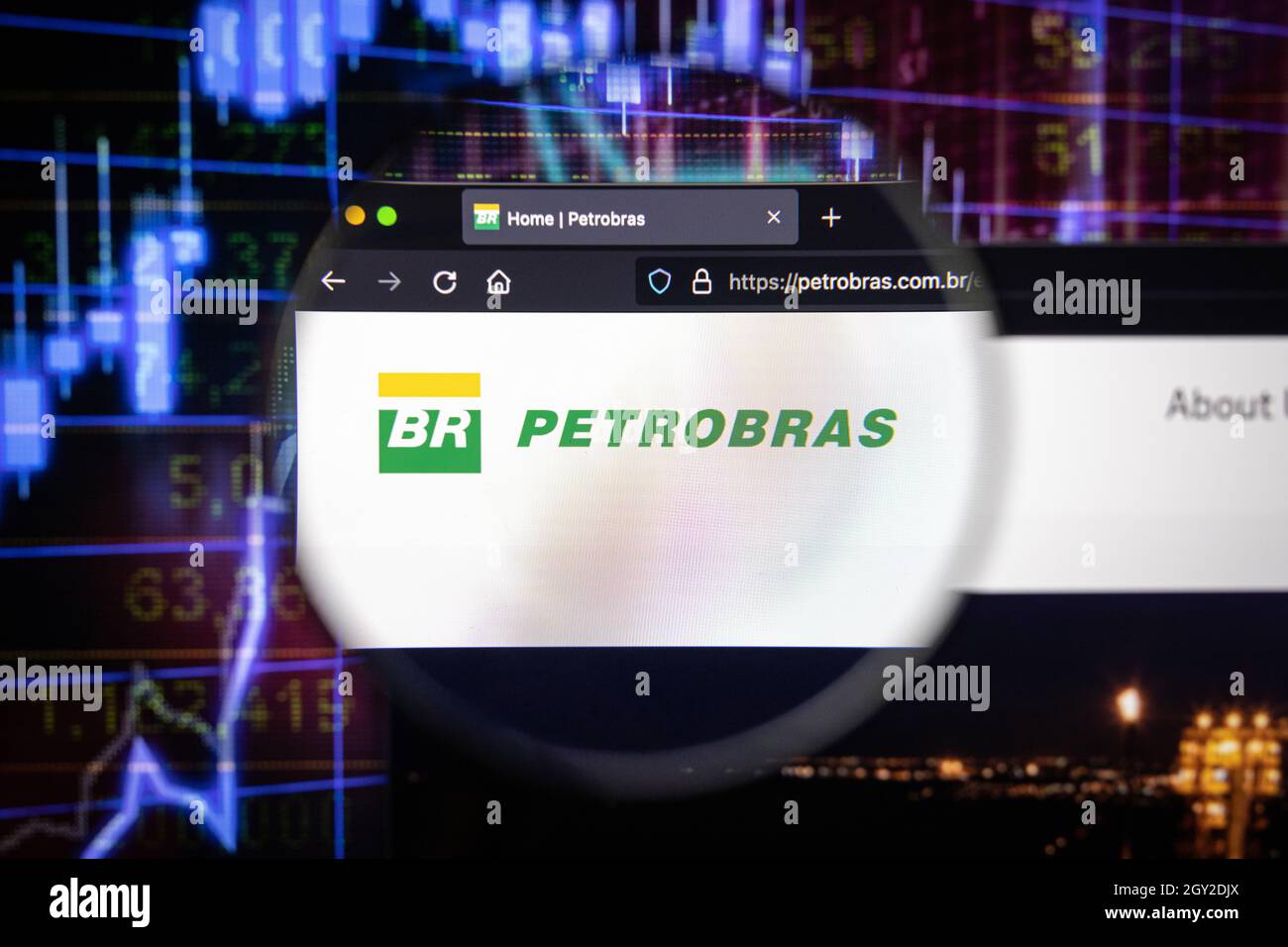 Logo de la société Petrobras sur un site Web avec des développements flous du marché boursier en arrière-plan, vu sur un écran d'ordinateur à travers une loupe Banque D'Images