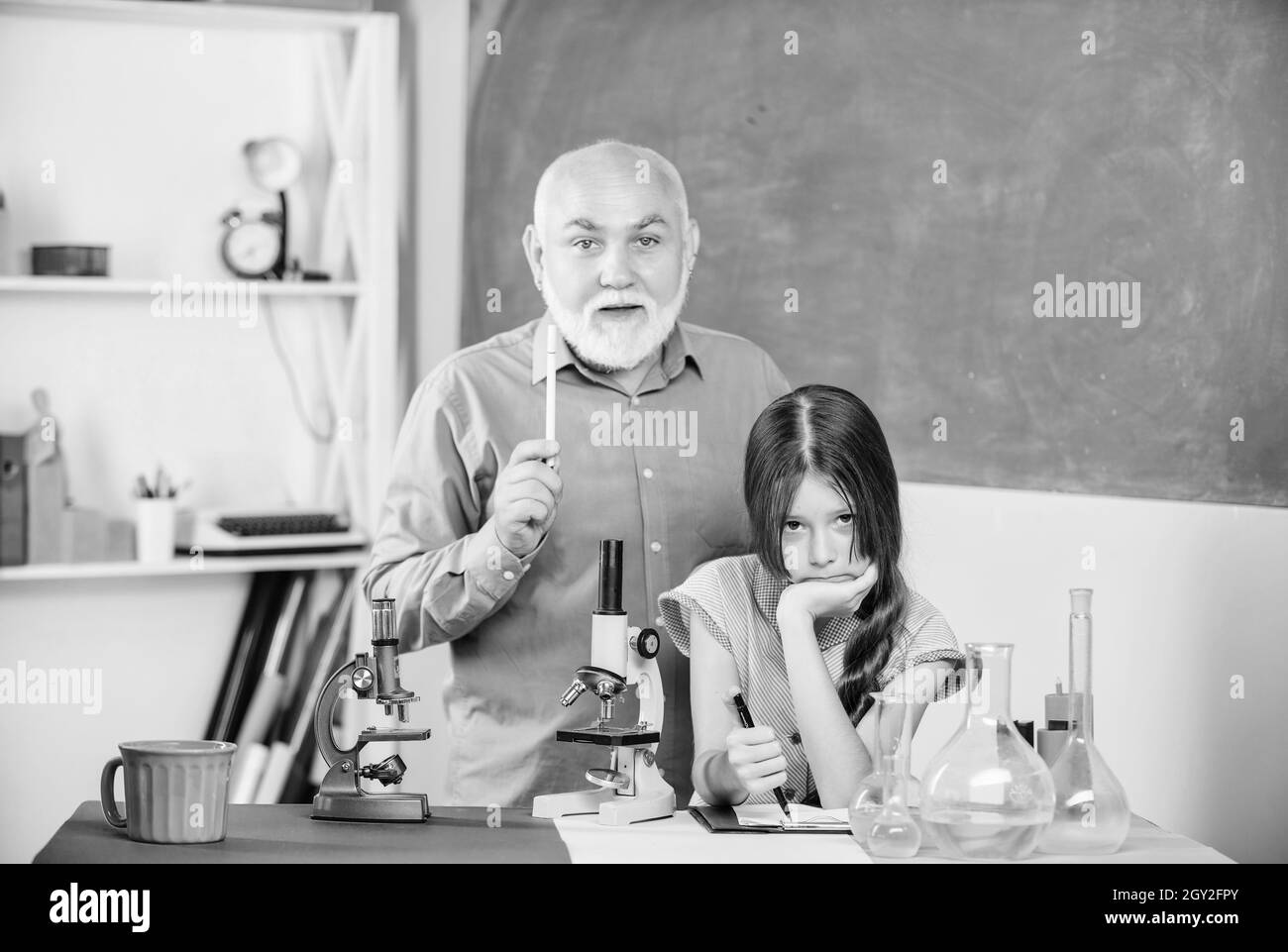 Où peu de choses signifient beaucoup. Utilisez la loupe. Professeur mature de biologie.Fille élève dans le laboratoire scolaire. Petite fille avec homme tuteur étudier la chimie Banque D'Images