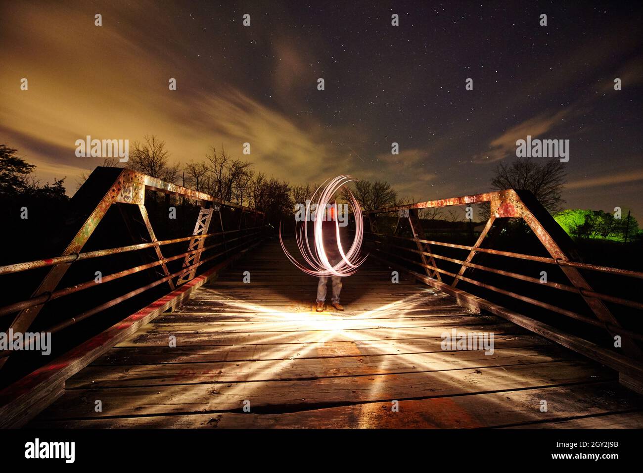 Lumière blanche tourbillonnante sur un pont métallique avec lumière qui traverse le pont lui-même au crépuscule Banque D'Images