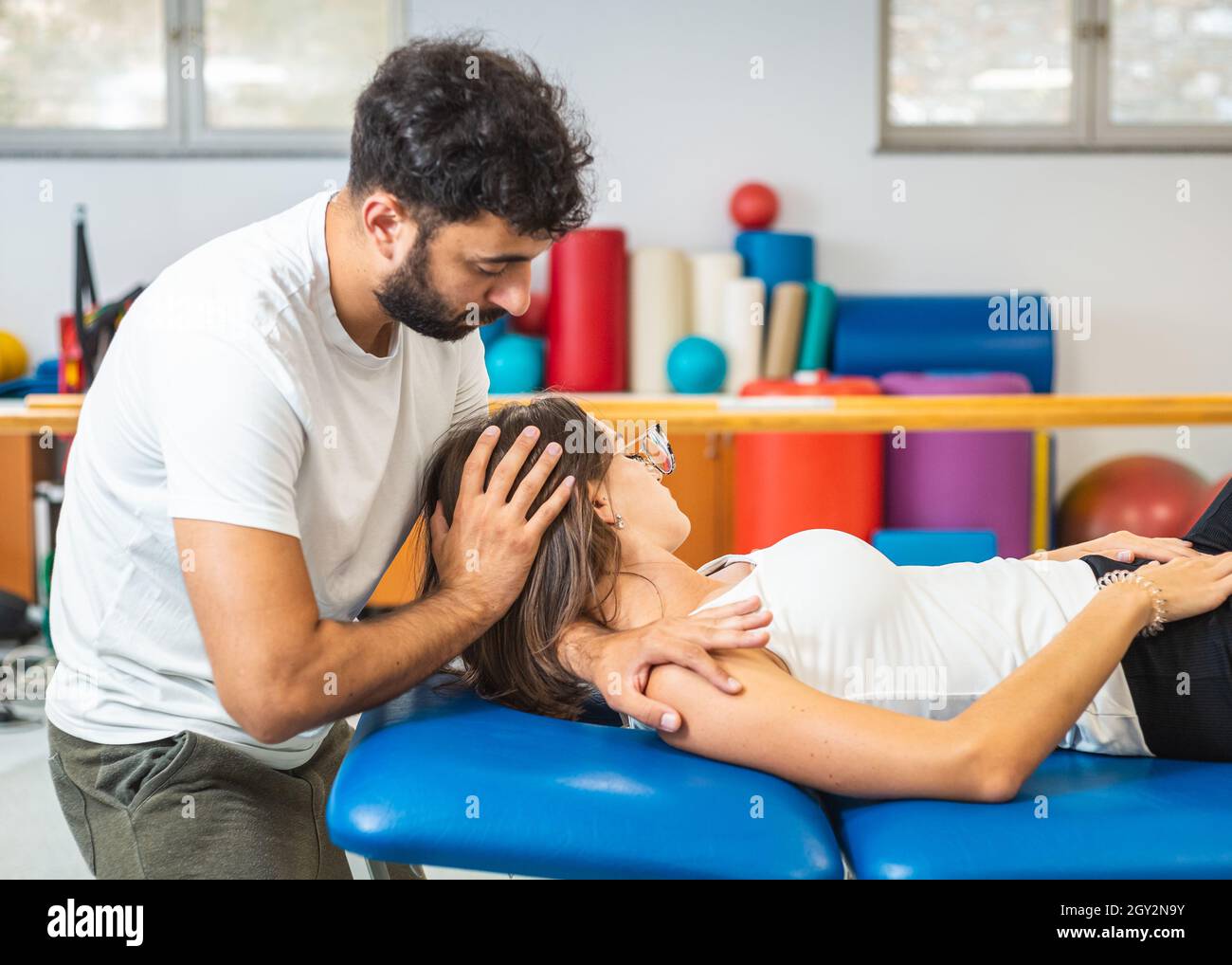 Physiothérapeute faisant des techniques manuelles d'étirement et de résistance pour réduire la douleur au cou chez une jeune femme caucasienne. Banque D'Images