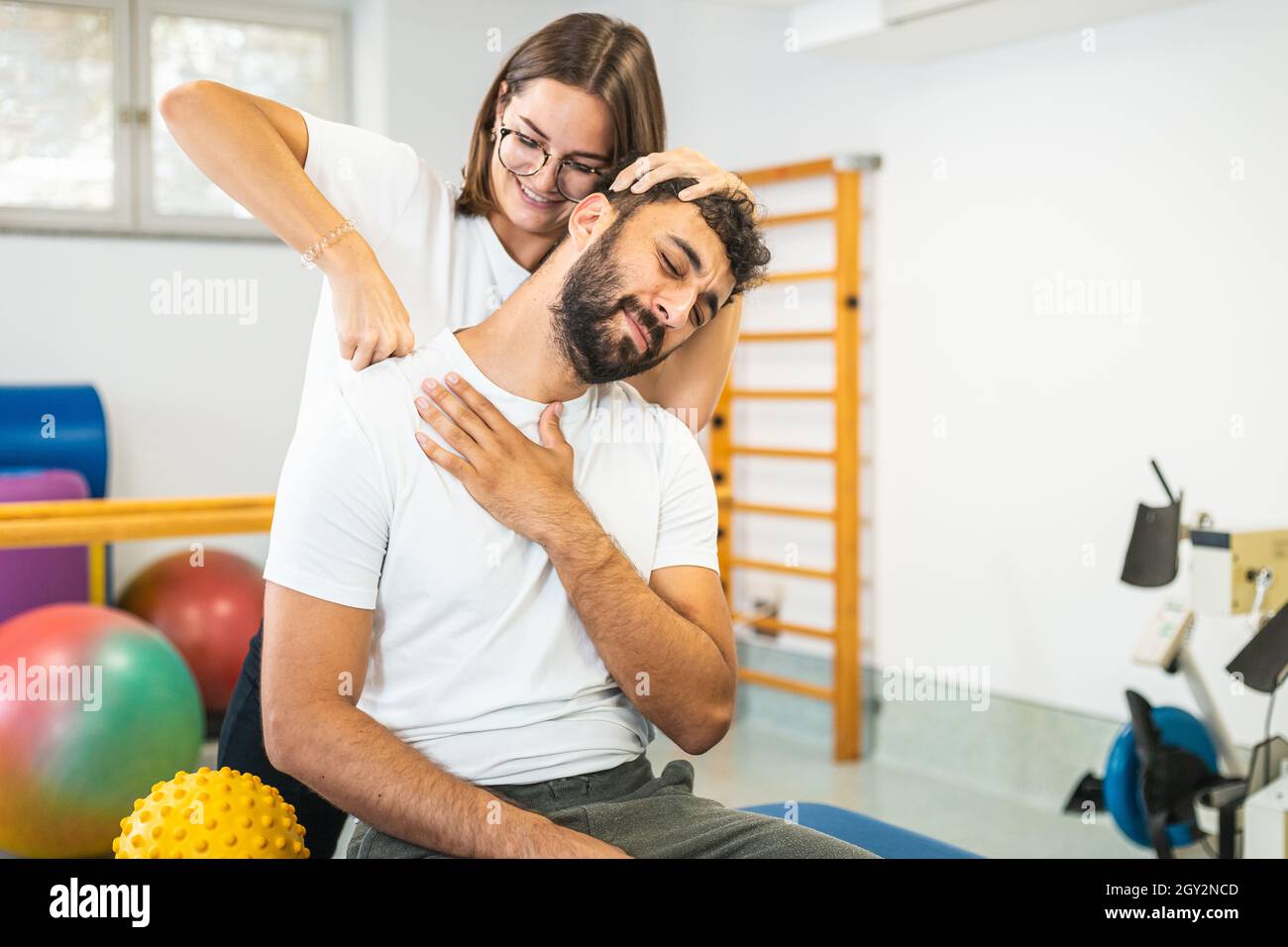 Femme thérapeute physique étirant le cou blessé d'un patient masculin. Banque D'Images