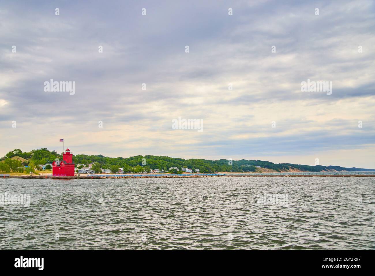 Vue sur le phare rouge avec grand lac et maisons de plage à distance Banque D'Images