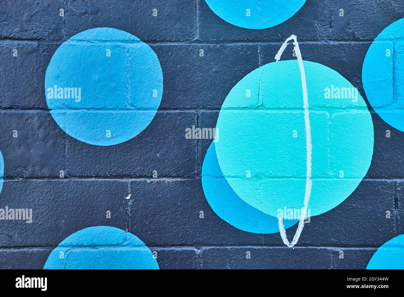 Mur peint en ciment noir avec taches bleues et planète sarcelle Banque D'Images