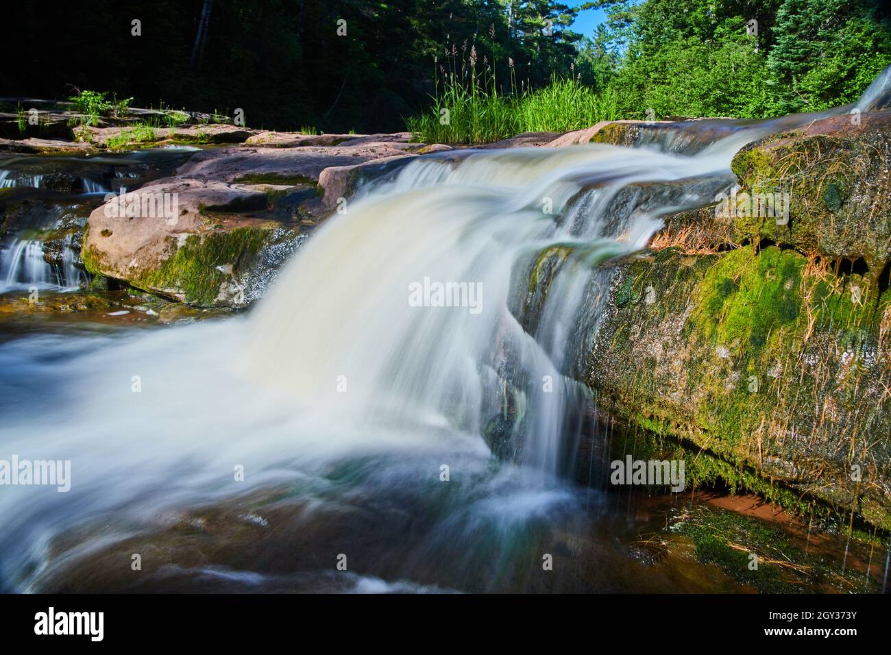Chutes d'eau se déversant sur des roches brunes couvertes de mousse humide Banque D'Images