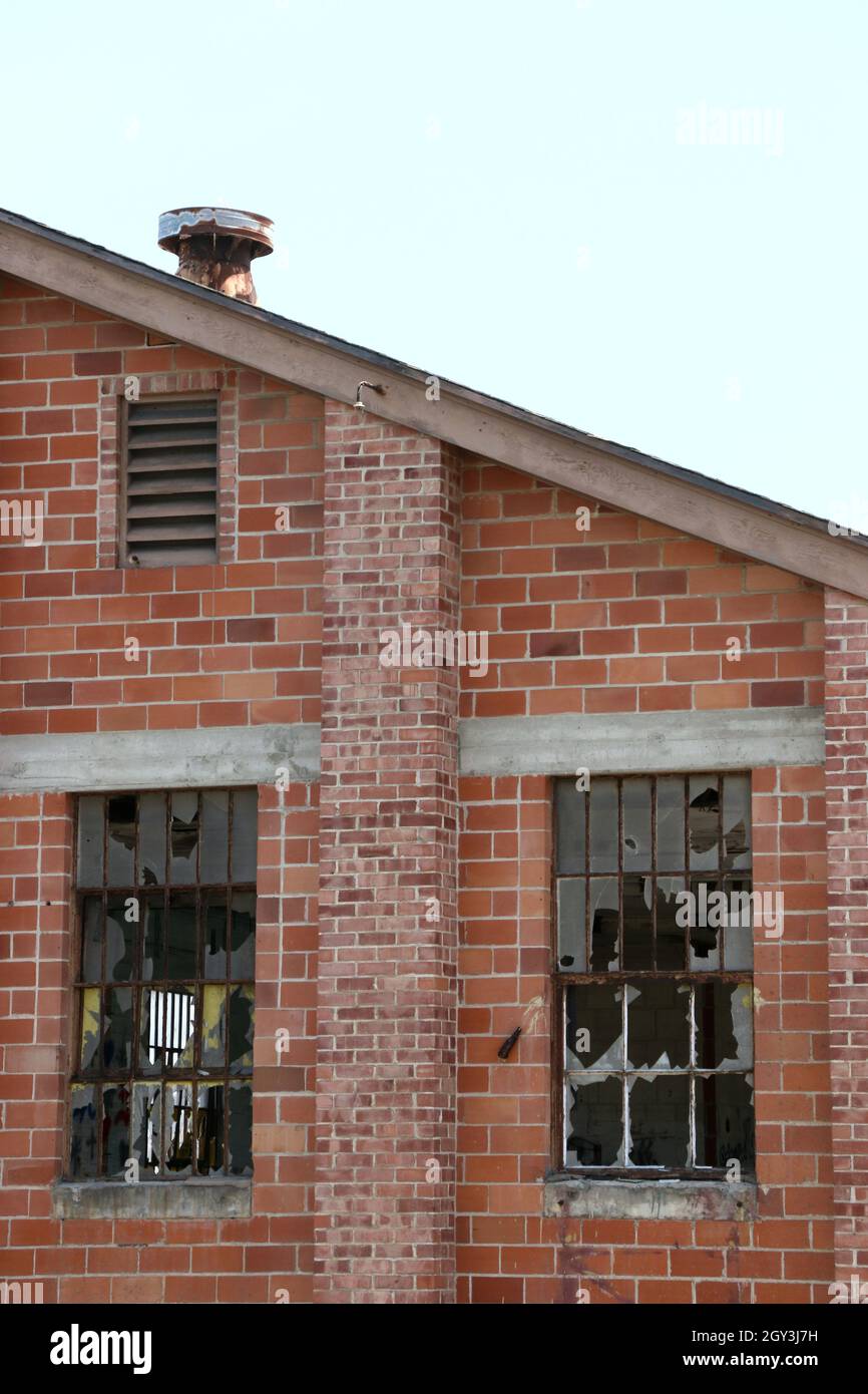 Entrepôt en briques abandonné et abandonné avec des fenêtres écrasées. Banque D'Images