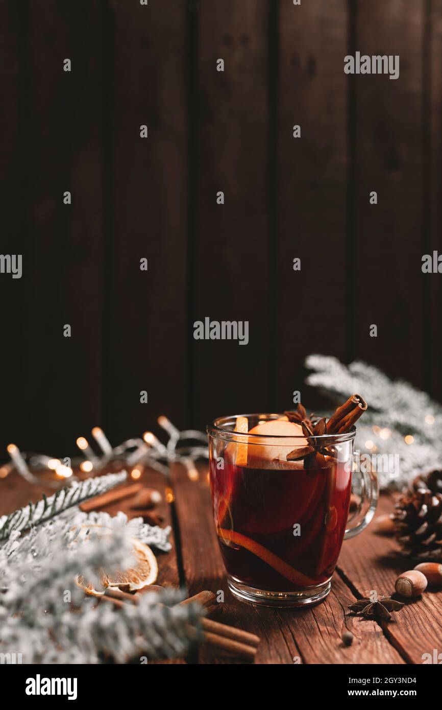 Photo concept de l'heure de Noël.Tasse ou mug en verre avec vin chaud à l'intérieur sur fond de table en bois.Décorations, cannelle, orange séché, pomme, divers Banque D'Images