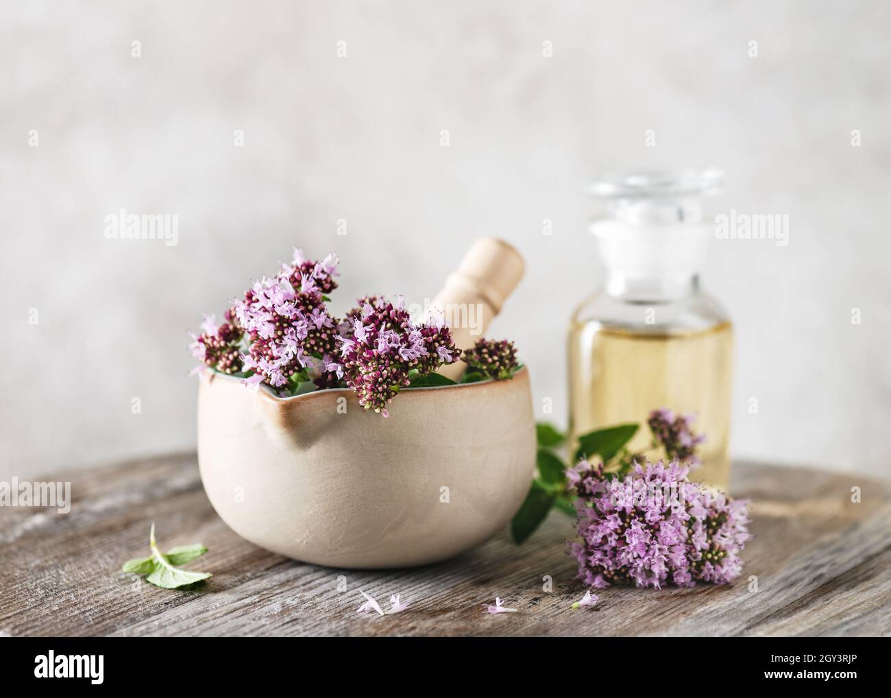 Brindilles fraîches en forme d'origan florissant dans le mortier en céramique et une bouteille d'huile.Fleurs d'herbes, feuilles utilisées dans la saison alimentaire et en médecine de fines herbes. Banque D'Images