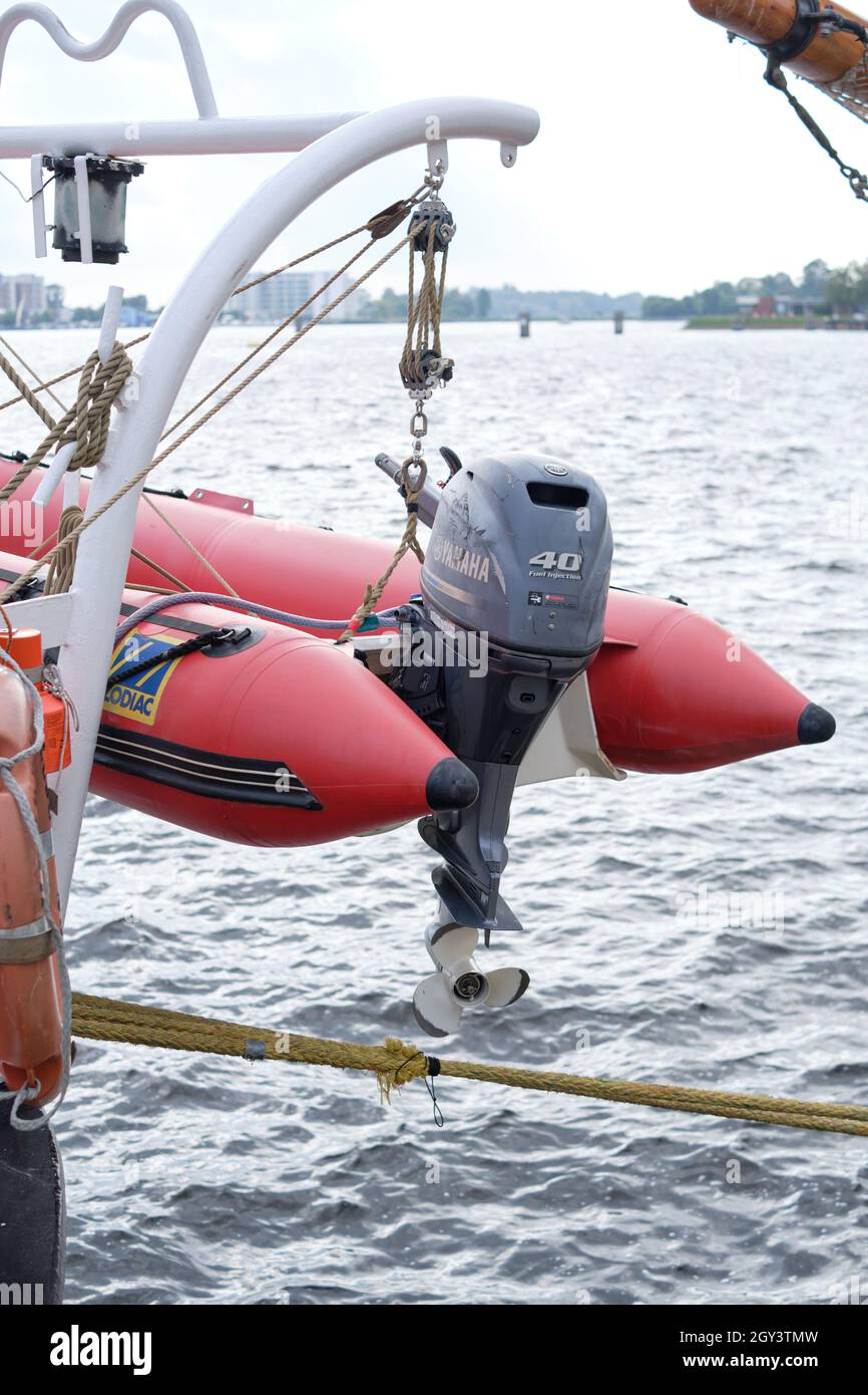 Plan vertical du bateau à moteur gonflable rouge suspendu au yacht à voile Banque D'Images
