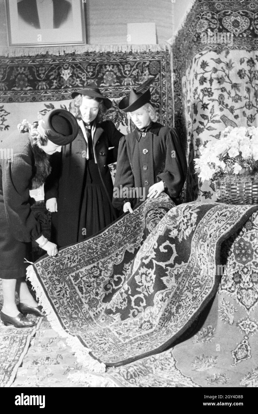 Messebesucher an einem Stand mit Perserteppigen, anlässlich der Wiener Modewoche im Haus der mode ' Palais Lobkowitz', Deutschland 1940er Jahre.Visiteurs à une foire sur un stand avec tapis persans, à l'occasion de la Wiener Modewoche dans la maison de la mode 'Palais Lobkowitz', Allemagne des années 1940. Banque D'Images